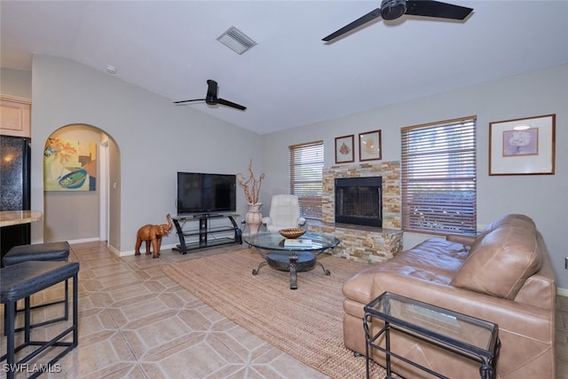 tiled living room with plenty of natural light, lofted ceiling, a stone fireplace, and ceiling fan