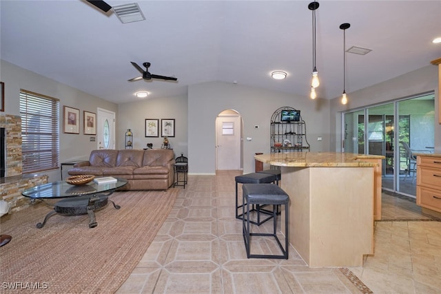 kitchen featuring light brown cabinetry, a center island, light stone countertops, light tile patterned floors, and a kitchen breakfast bar