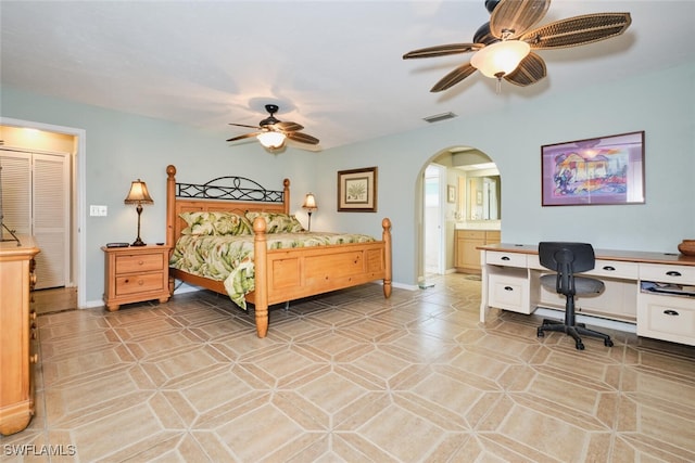 bedroom featuring ensuite bath, light tile patterned floors, and ceiling fan