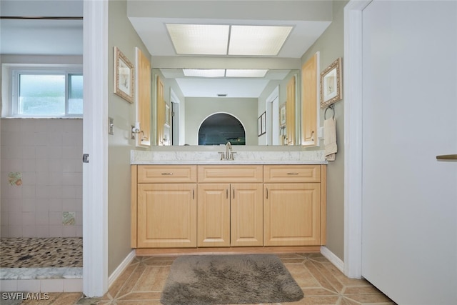 bathroom featuring tiled shower, vanity, and tile patterned floors