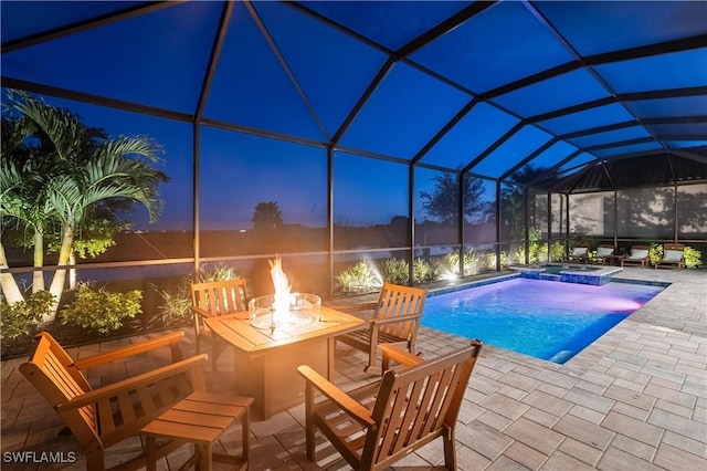 pool at dusk featuring a lanai, an in ground hot tub, and a patio area