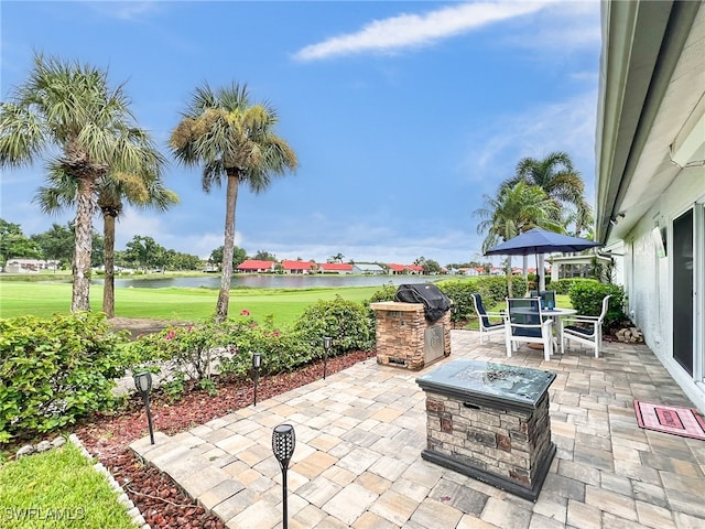 view of patio featuring area for grilling, a water view, a fire pit, and grilling area