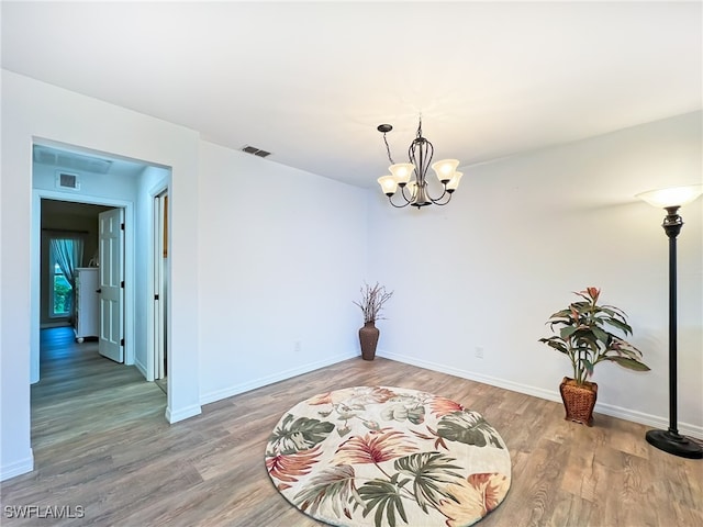 unfurnished room featuring hardwood / wood-style floors and a chandelier