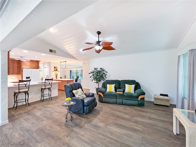 living room with ceiling fan, light wood-type flooring, and vaulted ceiling