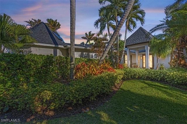 1303 Wahoo Ct, Naples, FL 34102 - back of house at dusk with stucco siding, a yard, and roof with shingles