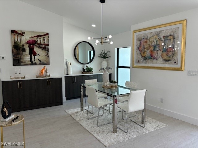 dining area with a notable chandelier, vaulted ceiling, and light wood-type flooring