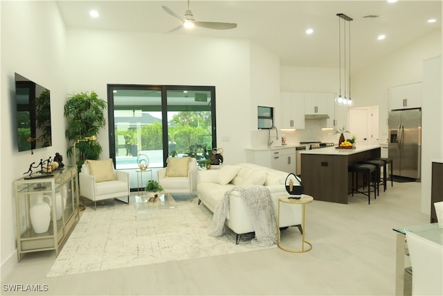 living room featuring ceiling fan, high vaulted ceiling, and sink