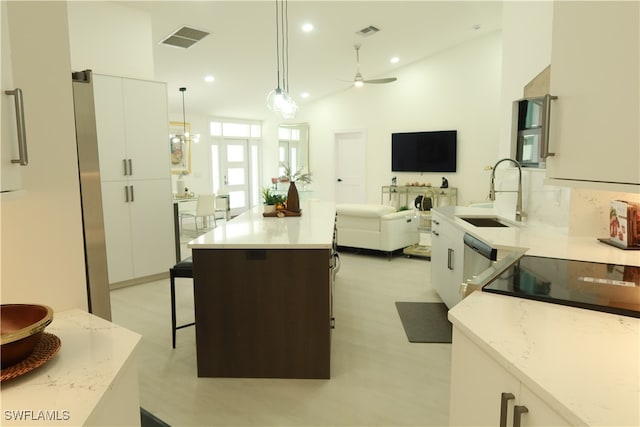 kitchen with ceiling fan, pendant lighting, white cabinetry, sink, and a center island