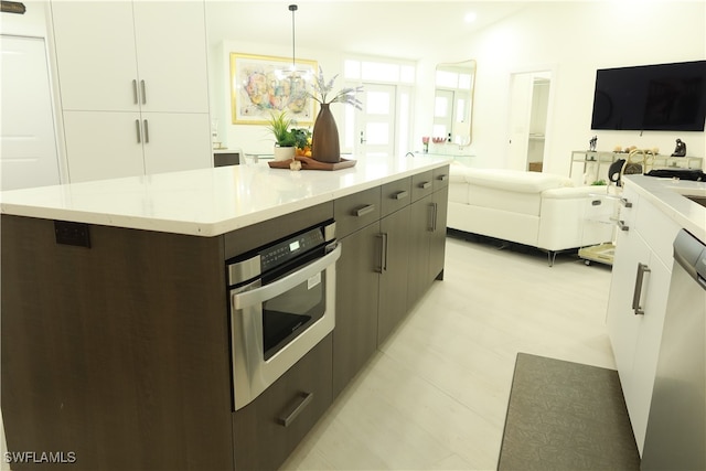 kitchen with dishwashing machine, decorative light fixtures, light stone countertops, a kitchen island, and oven