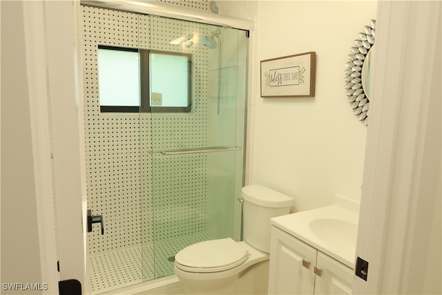 bathroom featuring a shower with shower door, toilet, and vanity