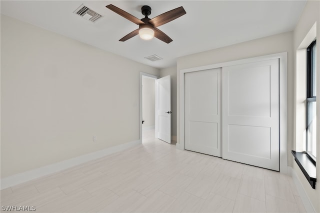 unfurnished bedroom featuring ceiling fan, multiple windows, and a closet