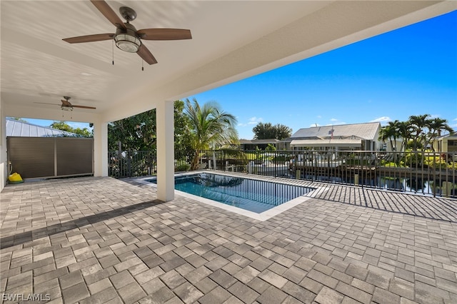 view of swimming pool with a patio, a water view, and ceiling fan