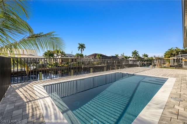 view of swimming pool featuring a patio and a water view