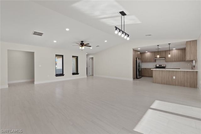 unfurnished living room with sink, vaulted ceiling, and ceiling fan