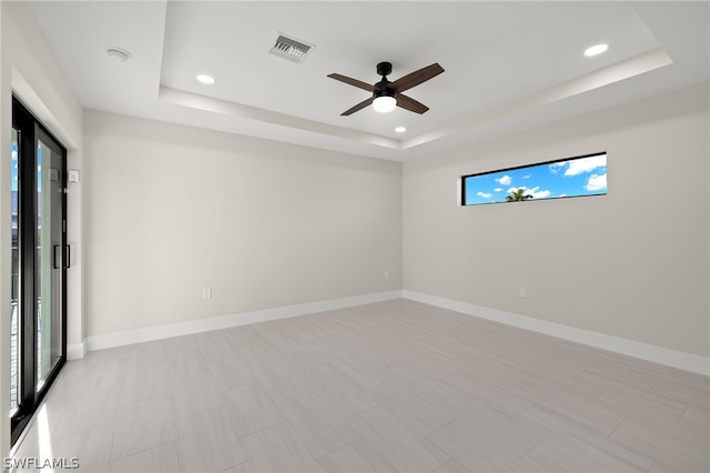 spare room with ceiling fan, plenty of natural light, and a raised ceiling