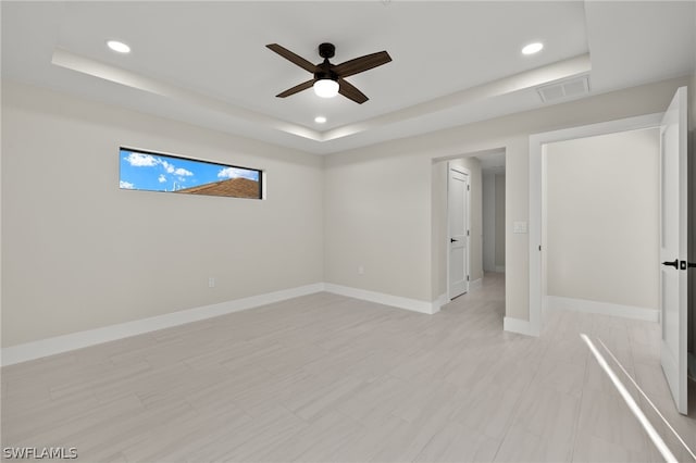 empty room featuring ceiling fan and a raised ceiling