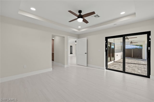 unfurnished room featuring a raised ceiling and ceiling fan