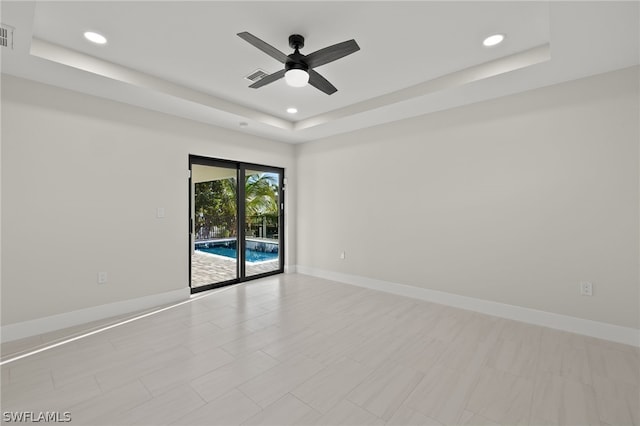 unfurnished room featuring ceiling fan and a raised ceiling