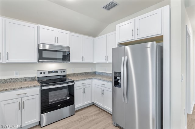 kitchen featuring appliances with stainless steel finishes, lofted ceiling, and white cabinets