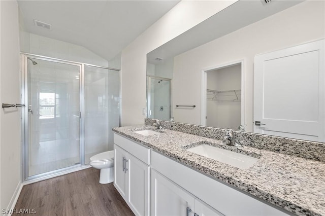 bathroom with an enclosed shower, lofted ceiling, wood-type flooring, vanity, and toilet