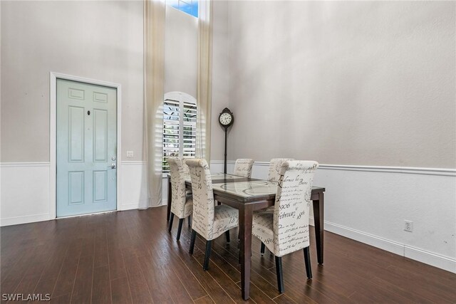 dining space with dark hardwood / wood-style flooring and a towering ceiling