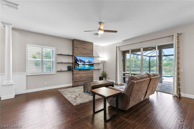 living room with decorative columns, ceiling fan, and dark hardwood / wood-style floors