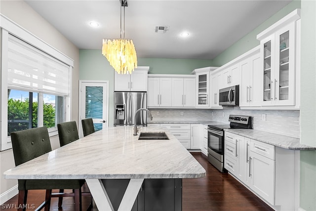 kitchen with tasteful backsplash, stainless steel appliances, sink, pendant lighting, and light stone counters