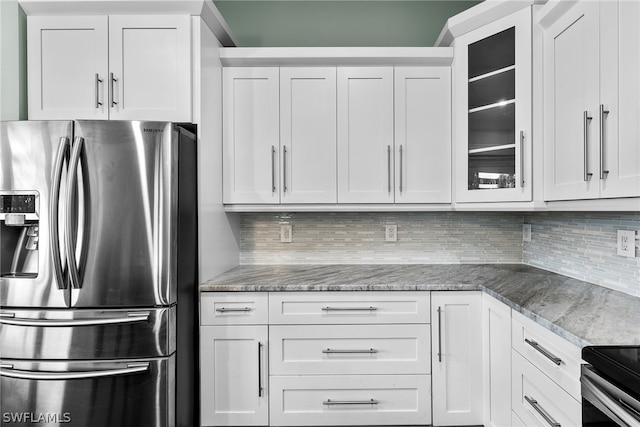 kitchen with stainless steel fridge, white cabinetry, light stone countertops, and backsplash