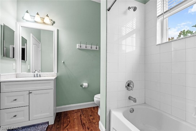 full bathroom with tiled shower / bath, vanity, toilet, and hardwood / wood-style floors