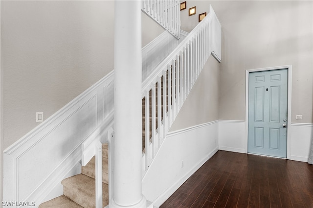 staircase with wood-type flooring and a high ceiling