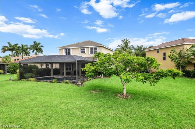 rear view of house with a patio, a yard, and a lanai