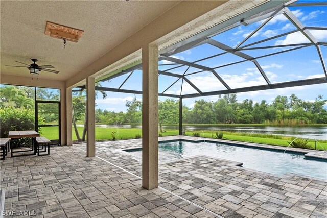 view of pool with pool water feature, a lanai, a water view, a patio area, and ceiling fan