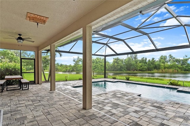 view of swimming pool with a lanai, pool water feature, ceiling fan, a water view, and a patio area