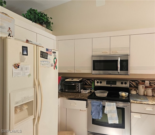 kitchen featuring dark stone countertops, stainless steel appliances, and white cabinetry