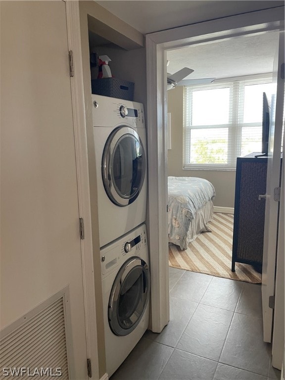 clothes washing area with stacked washer and clothes dryer and light tile patterned floors