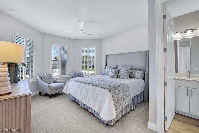 bedroom with ensuite bathroom, sink, light hardwood / wood-style flooring, and ceiling fan