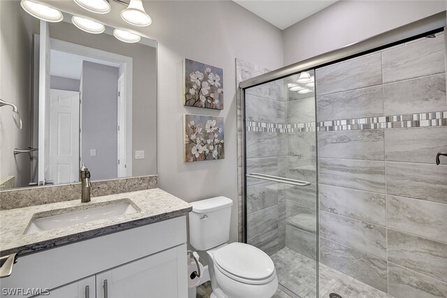 bathroom with toilet, vanity, and an enclosed shower