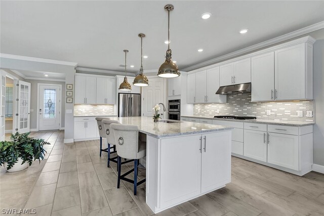 kitchen with crown molding, appliances with stainless steel finishes, tasteful backsplash, and an island with sink