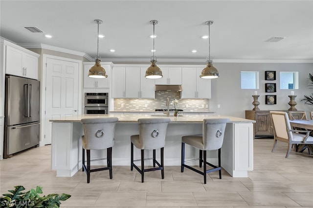20012 Tavernier Dr, Estero, FL 33928 - kitchen featuring visible vents, stainless steel appliances, under cabinet range hood, white cabinetry, and a spacious island