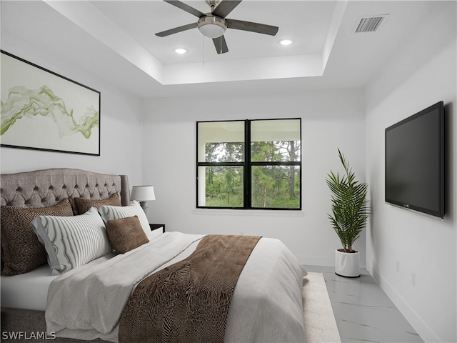 bedroom with ceiling fan, a tray ceiling, and light tile patterned floors