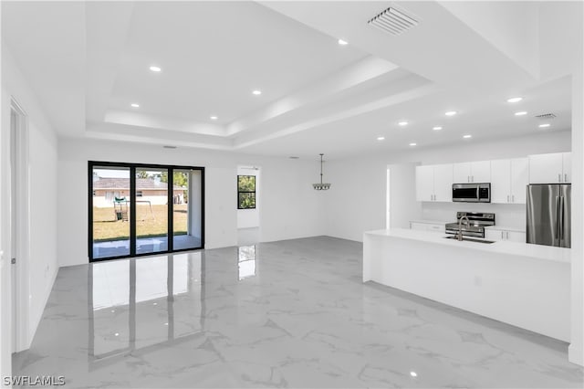 kitchen with appliances with stainless steel finishes, white cabinets, sink, light tile patterned flooring, and a tray ceiling