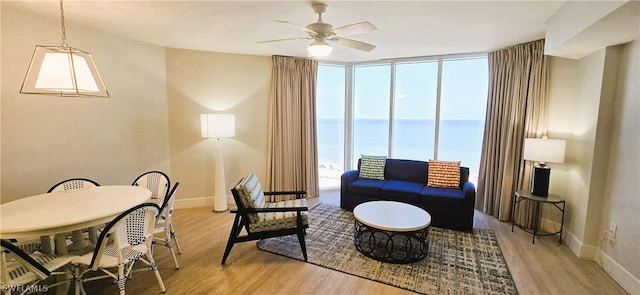 living room featuring plenty of natural light, a water view, light hardwood / wood-style flooring, and a wall of windows