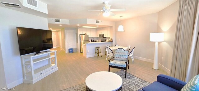 living room with light hardwood / wood-style flooring and ceiling fan