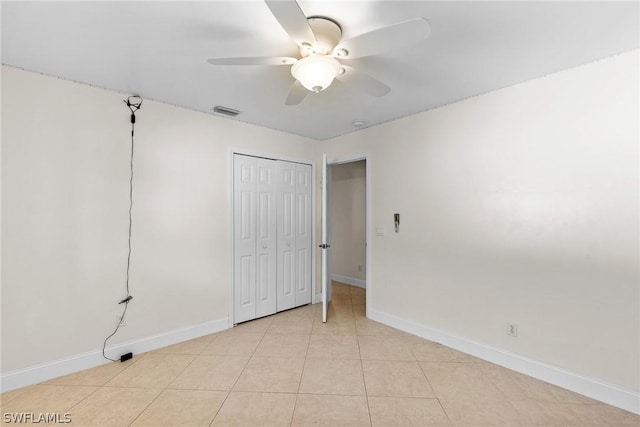 unfurnished bedroom with light tile patterned floors, a closet, and ceiling fan