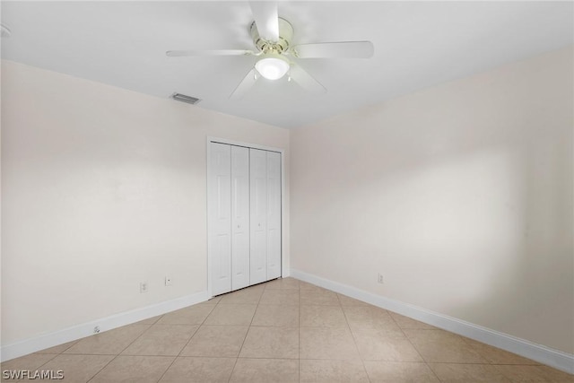 unfurnished bedroom featuring ceiling fan, a closet, and light tile patterned floors