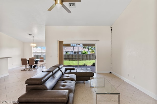 tiled living room with ceiling fan with notable chandelier