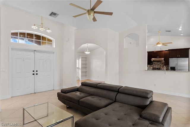 tiled living room with ceiling fan and high vaulted ceiling