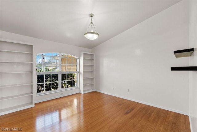 interior space featuring vaulted ceiling, hardwood / wood-style floors, and built in features