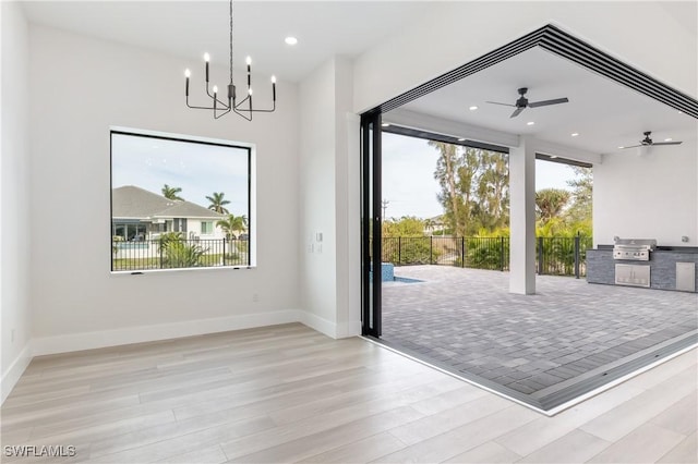 doorway to outside featuring ceiling fan with notable chandelier and light hardwood / wood-style flooring