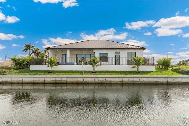 back of property featuring a water view, a balcony, and a lawn